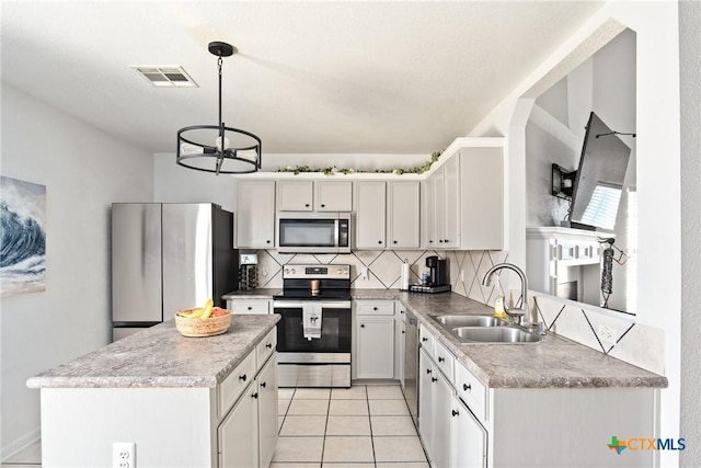 5607 Schorn Dr, Killeen, TX 76542 - kitchen featuring appliances with stainless steel finishes, a sink, tasteful backsplash, a kitchen island, and hanging light fixtures