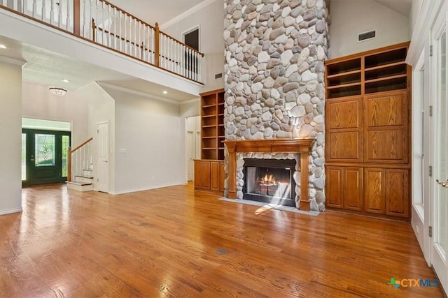 11740 Stinnett Mill Rd, Salado, TX 76571 - unfurnished living room featuring a towering ceiling, wood finished floors, a fireplace, stairs, and crown molding