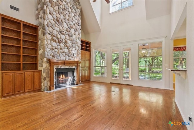 11740 Stinnett Mill Rd, Salado, TX 76571 - unfurnished living room featuring wood finished floors, a stone fireplace, a ceiling fan, and a towering ceiling
