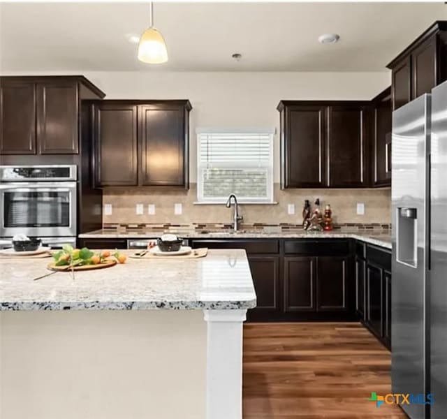 5561 Perdita Dr, Belton, TX 76513 - kitchen with dark brown cabinetry, light stone countertops, wood finished floors, appliances with stainless steel finishes, and a sink