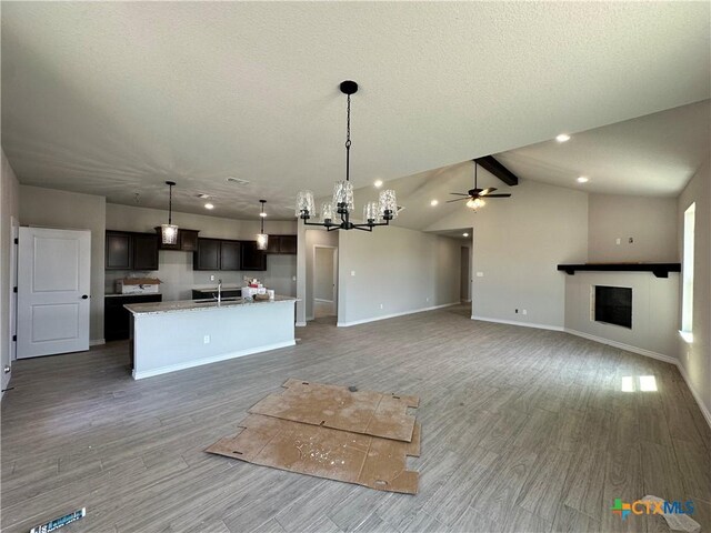 2598 Settlers Oak Dr, Belton, TX 76513 - unfurnished living room with a sink, a chandelier, baseboards, light wood-type flooring, and a textured ceiling