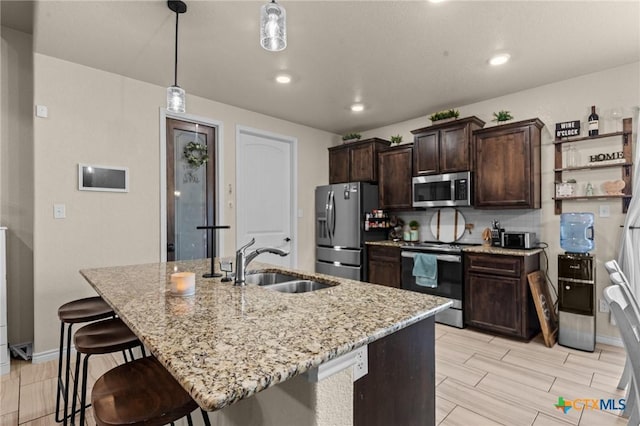2311 Sparrow Rd, Killeen, TX 76542 - kitchen featuring appliances with stainless steel finishes, a sink, a kitchen island with sink, light stone countertops, and dark brown cabinets