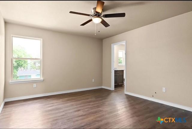 spare room featuring dark wood-type flooring, baseboards, and a ceiling fan