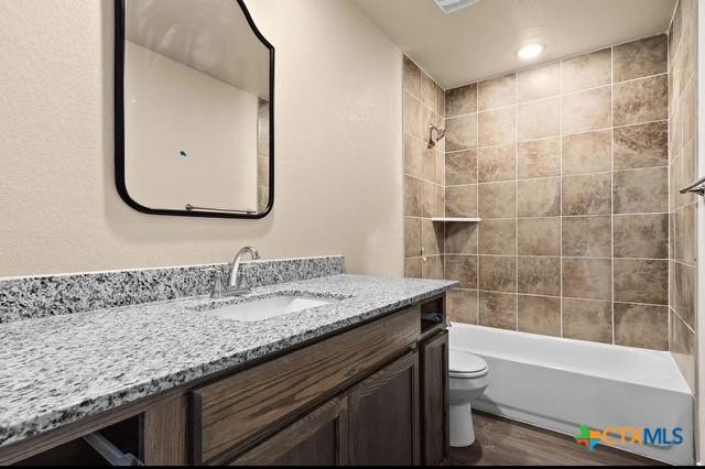 full bath featuring toilet, shower / washtub combination, vanity, and wood finished floors