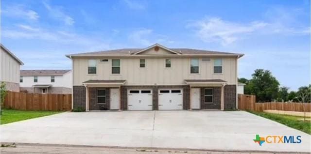 view of front of house featuring concrete driveway, fence, and a garage