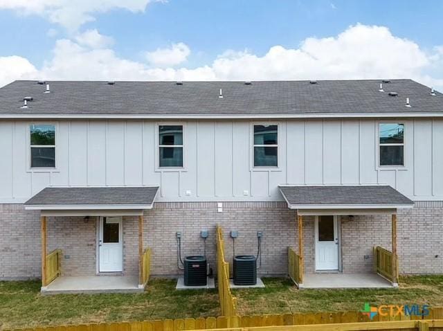 rear view of property featuring a patio area, a yard, board and batten siding, and central air condition unit
