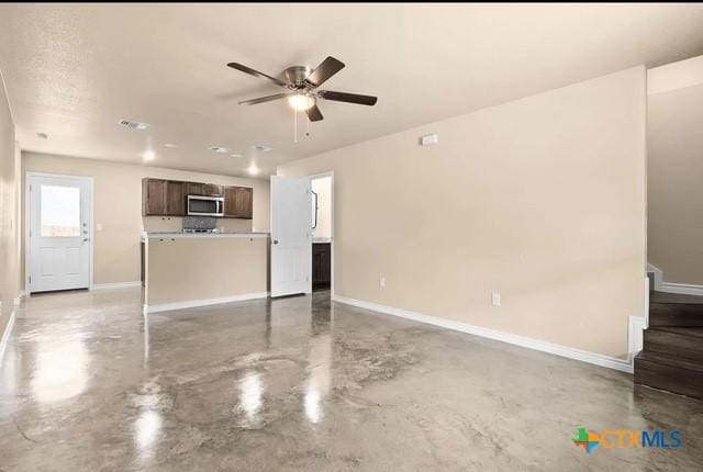 unfurnished living room featuring concrete floors, ceiling fan, baseboards, and stairs