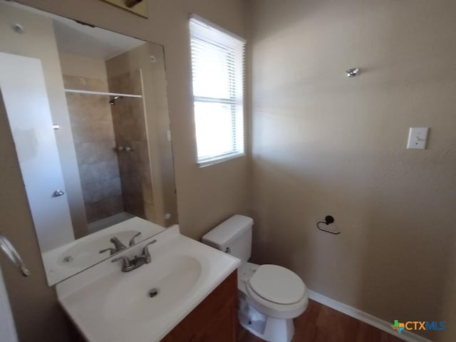 bathroom featuring vanity, hardwood / wood-style floors, toilet, and tiled shower