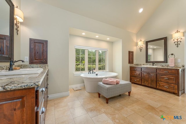 full bath with a sink, two vanities, vaulted ceiling, and a soaking tub