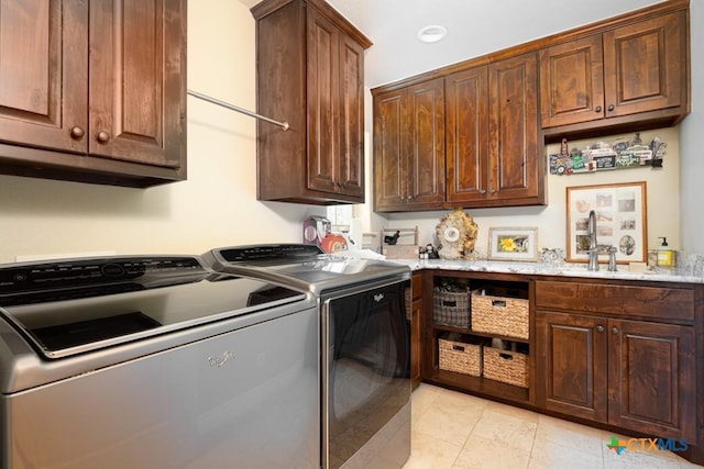 clothes washing area featuring cabinet space, light tile patterned floors, washing machine and dryer, and a sink