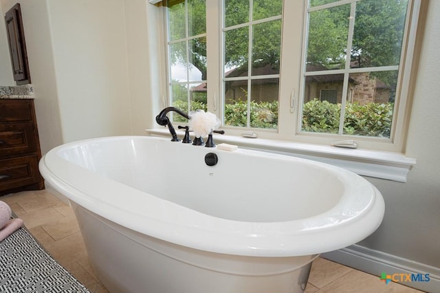 bathroom with a freestanding bath and tile patterned flooring