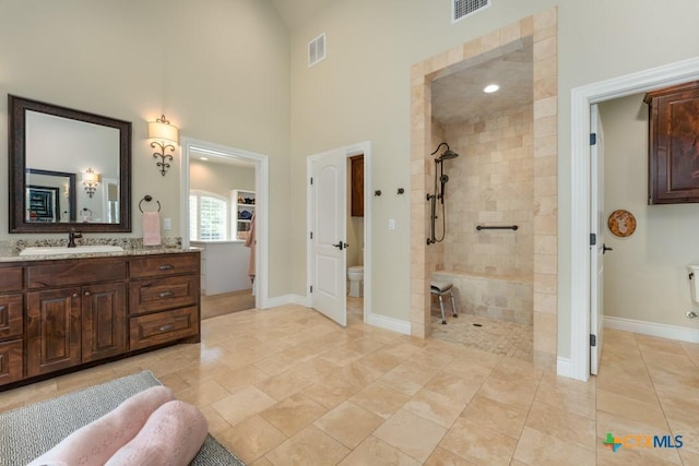 full bathroom with a towering ceiling, visible vents, walk in shower, vanity, and toilet