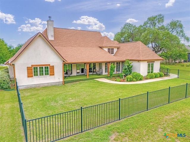 back of property featuring a fenced backyard, a chimney, a lawn, and stucco siding