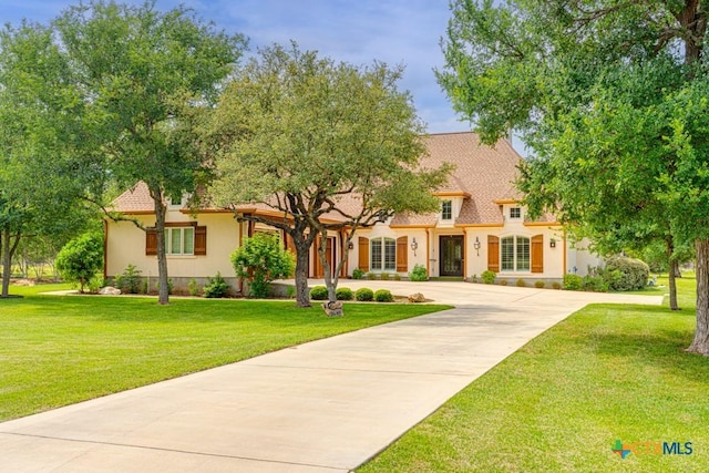 view of front of property featuring stucco siding, concrete driveway, and a front lawn