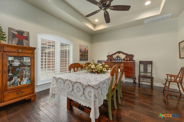 dining room with baseboards, a tray ceiling, dark wood-style floors, and visible vents