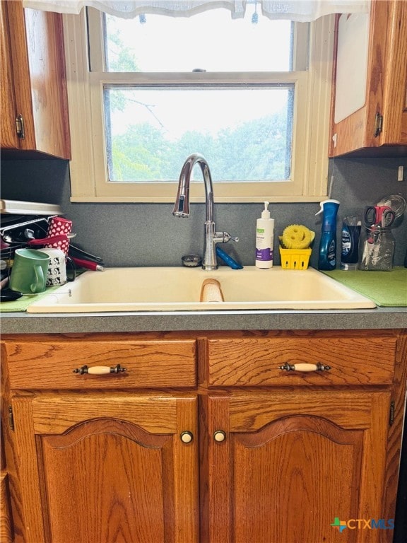 2405 Oak Dr, Gatesville, TX 76528 - kitchen featuring a sink, brown cabinetry, and light countertops