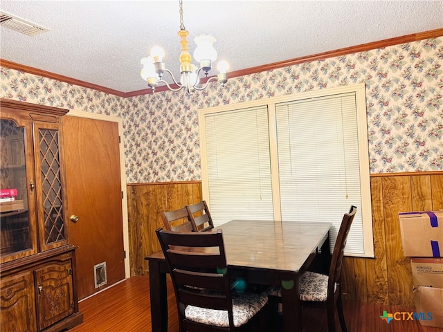 2405 Oak Dr, Gatesville, TX 76528 - dining space with a chandelier, a wainscoted wall, wood walls, wallpapered walls, and wood finished floors