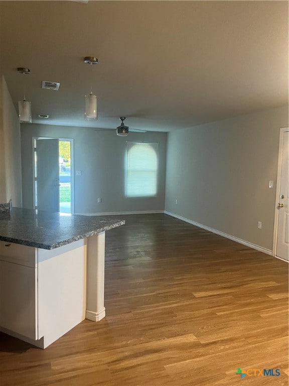 kitchen featuring dark stone counters, white cabinetry, decorative light fixtures, hardwood / wood-style flooring, and ceiling fan