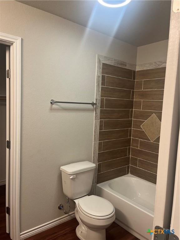 bathroom with hardwood / wood-style floors, toilet, and tiled shower / bath combo