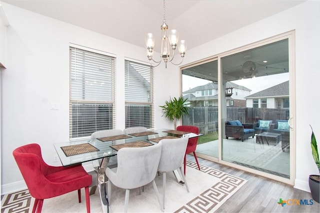 dining space with lofted ceiling, hardwood / wood-style floors, and a notable chandelier