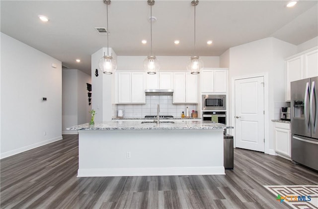 kitchen featuring light stone counters, appliances with stainless steel finishes, decorative light fixtures, and white cabinets