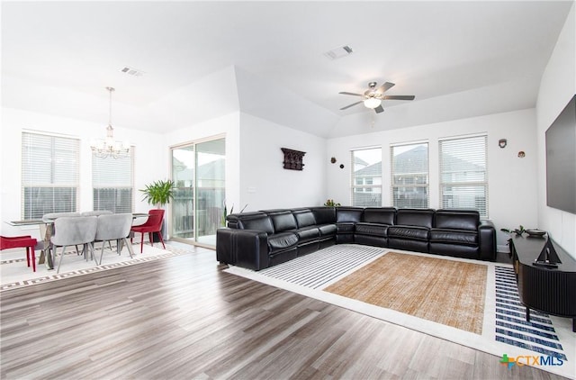 living room with ceiling fan with notable chandelier and hardwood / wood-style floors