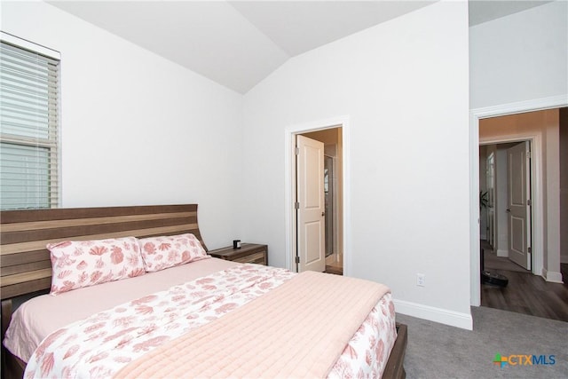 bedroom featuring lofted ceiling and dark carpet