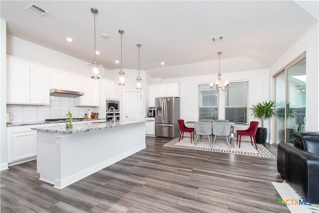 kitchen with white cabinetry, a center island with sink, appliances with stainless steel finishes, pendant lighting, and backsplash