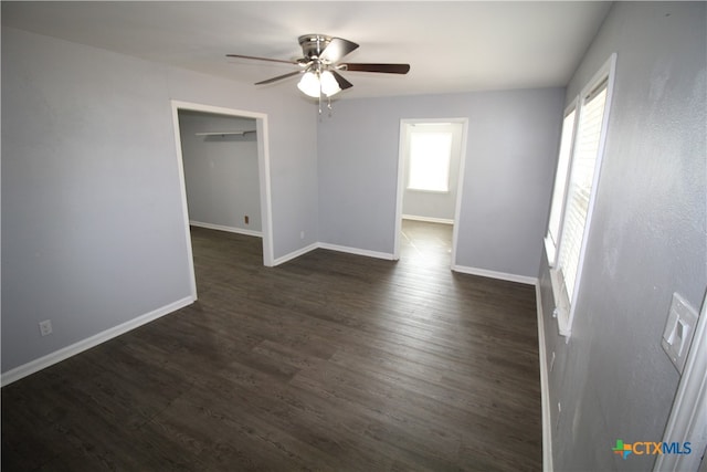 empty room featuring dark wood-type flooring, ceiling fan, and plenty of natural light