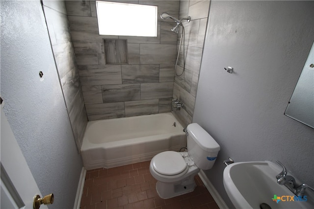 full bathroom featuring toilet, tiled shower / bath, sink, and tile patterned floors