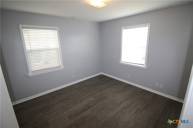 empty room featuring plenty of natural light and dark hardwood / wood-style floors