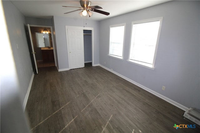 unfurnished bedroom with a closet, dark hardwood / wood-style flooring, ceiling fan, and connected bathroom