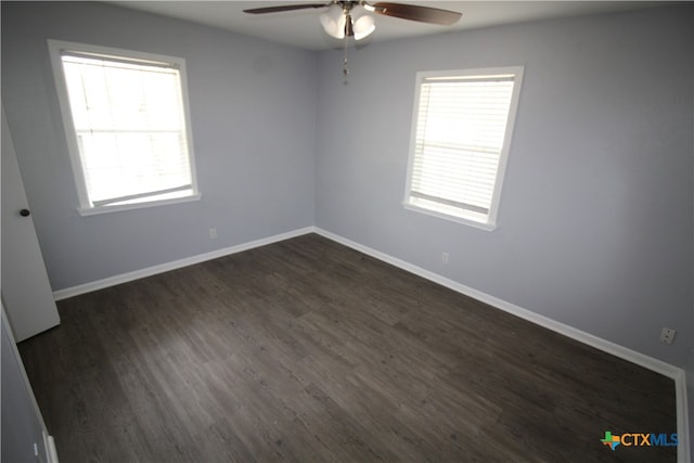 empty room with dark hardwood / wood-style flooring, a wealth of natural light, and ceiling fan