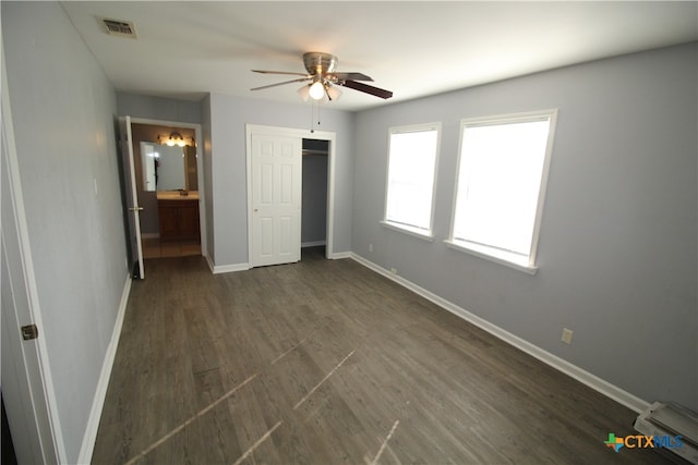 unfurnished bedroom with dark wood-type flooring, ceiling fan, and ensuite bathroom