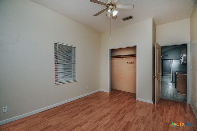 unfurnished bedroom featuring hardwood / wood-style flooring, ceiling fan, and a closet