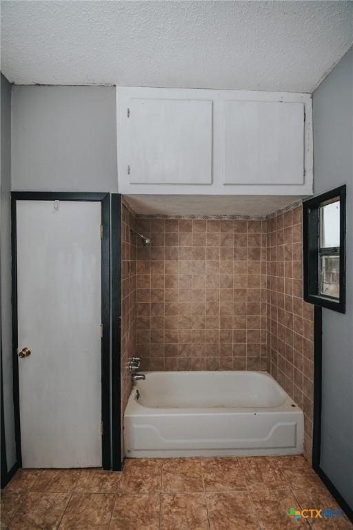 bathroom with tiled shower / bath and a textured ceiling