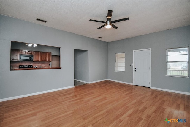 unfurnished living room featuring a textured ceiling, ceiling fan, and light wood-type flooring