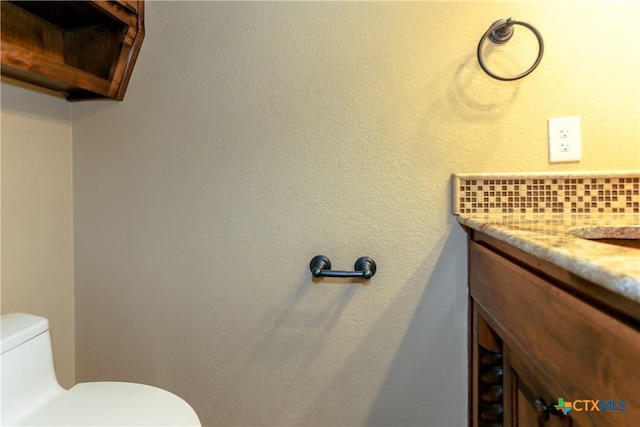 bathroom featuring vanity, decorative backsplash, and toilet