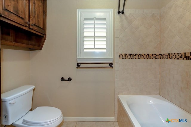 bathroom featuring a relaxing tiled tub, tile patterned floors, and toilet