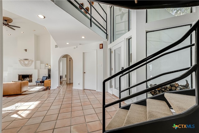 entryway with ceiling fan, light tile patterned flooring, and high vaulted ceiling