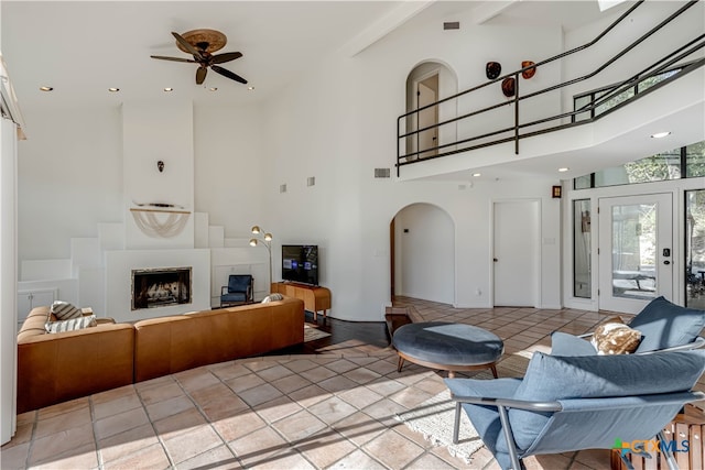 living room featuring beamed ceiling, ceiling fan, a towering ceiling, and light tile patterned floors