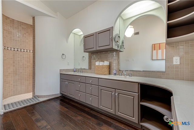 bathroom with walk in shower, tasteful backsplash, hardwood / wood-style floors, vanity, and tile walls