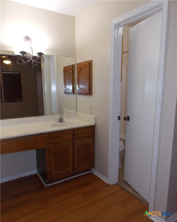 bathroom with hardwood / wood-style floors, vanity, and toilet