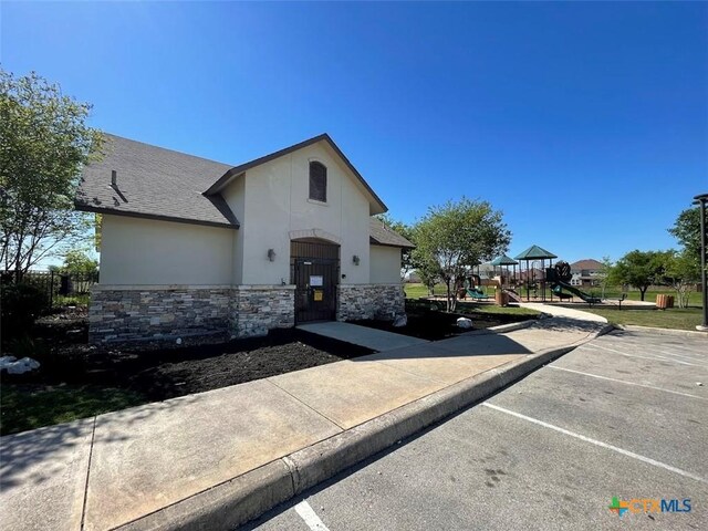 2092 Brandywine Dr, New Braunfels, TX 78130 - french country inspired facade with stone siding, uncovered parking, a playground, stucco siding, and a shingled roof