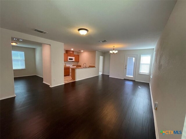 2092 Brandywine Dr, New Braunfels, TX 78130 - unfurnished living room featuring a chandelier, dark wood-style flooring, baseboards, and a sink
