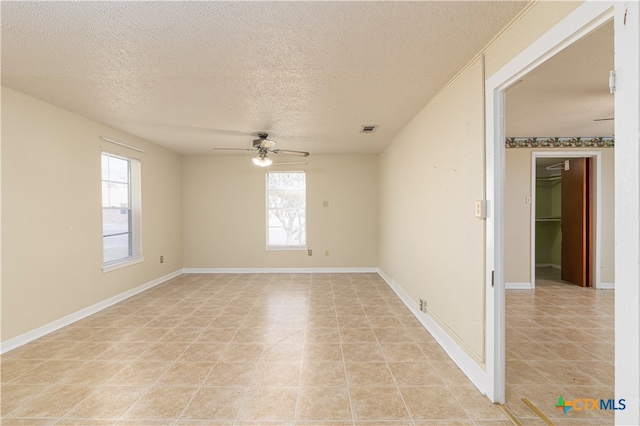 spare room featuring light tile patterned flooring, a textured ceiling, and ceiling fan