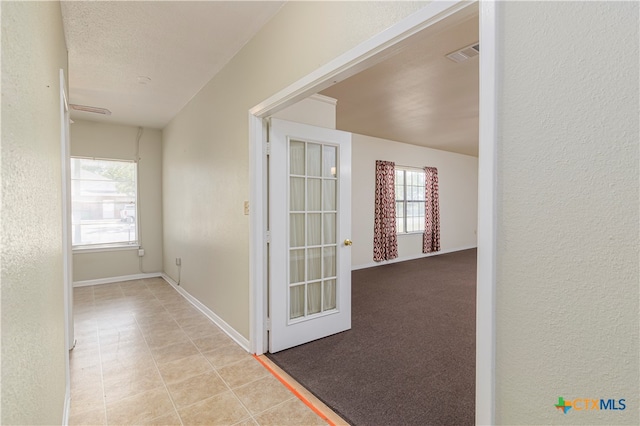 corridor with a textured ceiling and light carpet