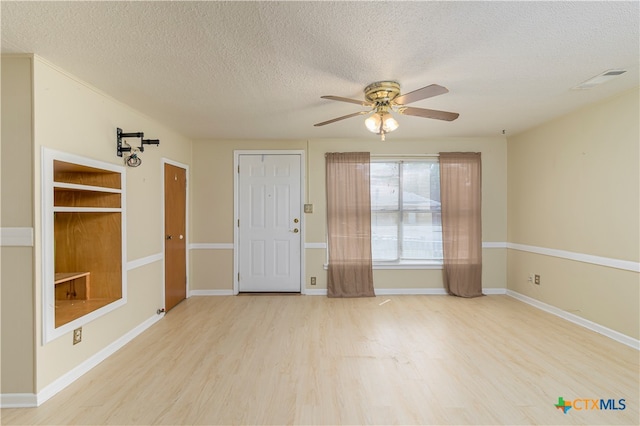 empty room with light wood-type flooring, a textured ceiling, and ceiling fan