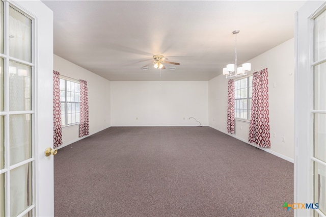 unfurnished room with dark colored carpet and ceiling fan with notable chandelier