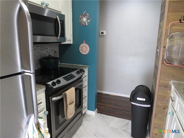 310 Rattan Dr, Victoria, TX 77901 - kitchen featuring appliances with stainless steel finishes, backsplash, white cabinetry, and light stone countertops